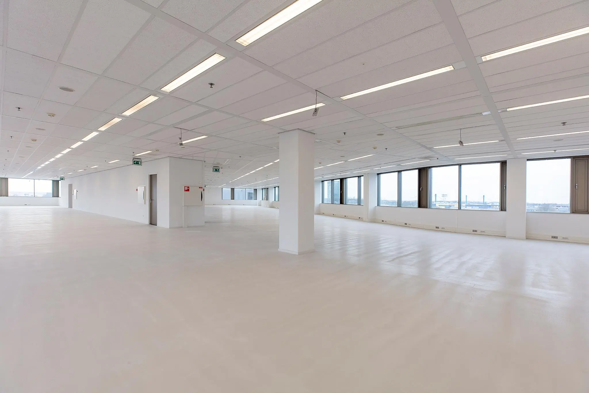 Lichte, open kantoorruimte aan de Vliegend Hertlaan met grote ramen en systeemplafond.